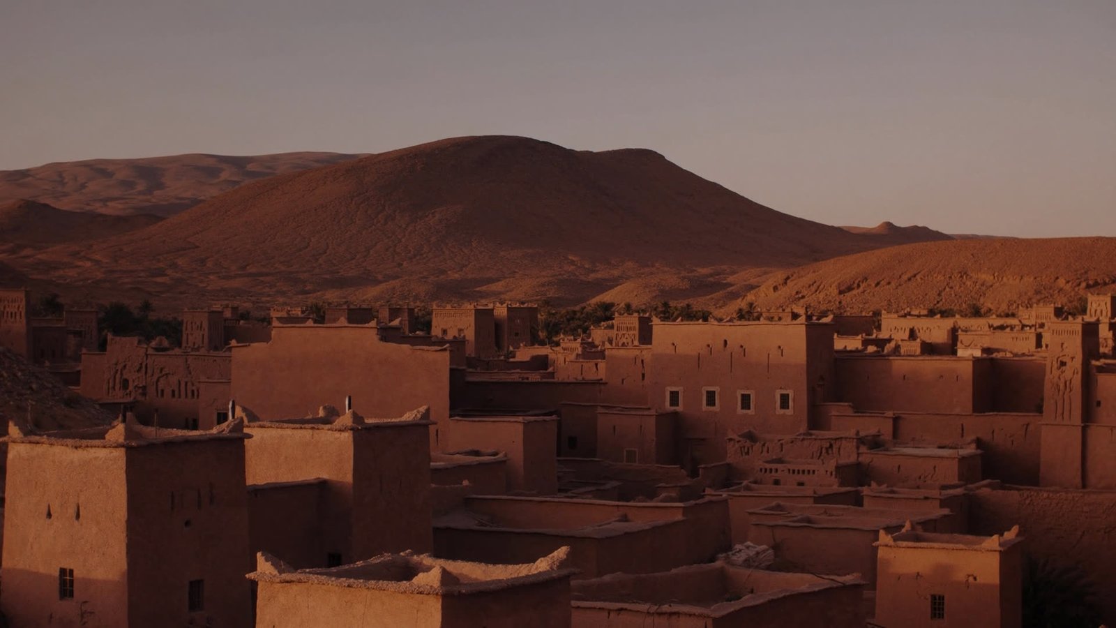 Kasbah architecture of Ouarzazate and its arid hills in warm late-afternoon light