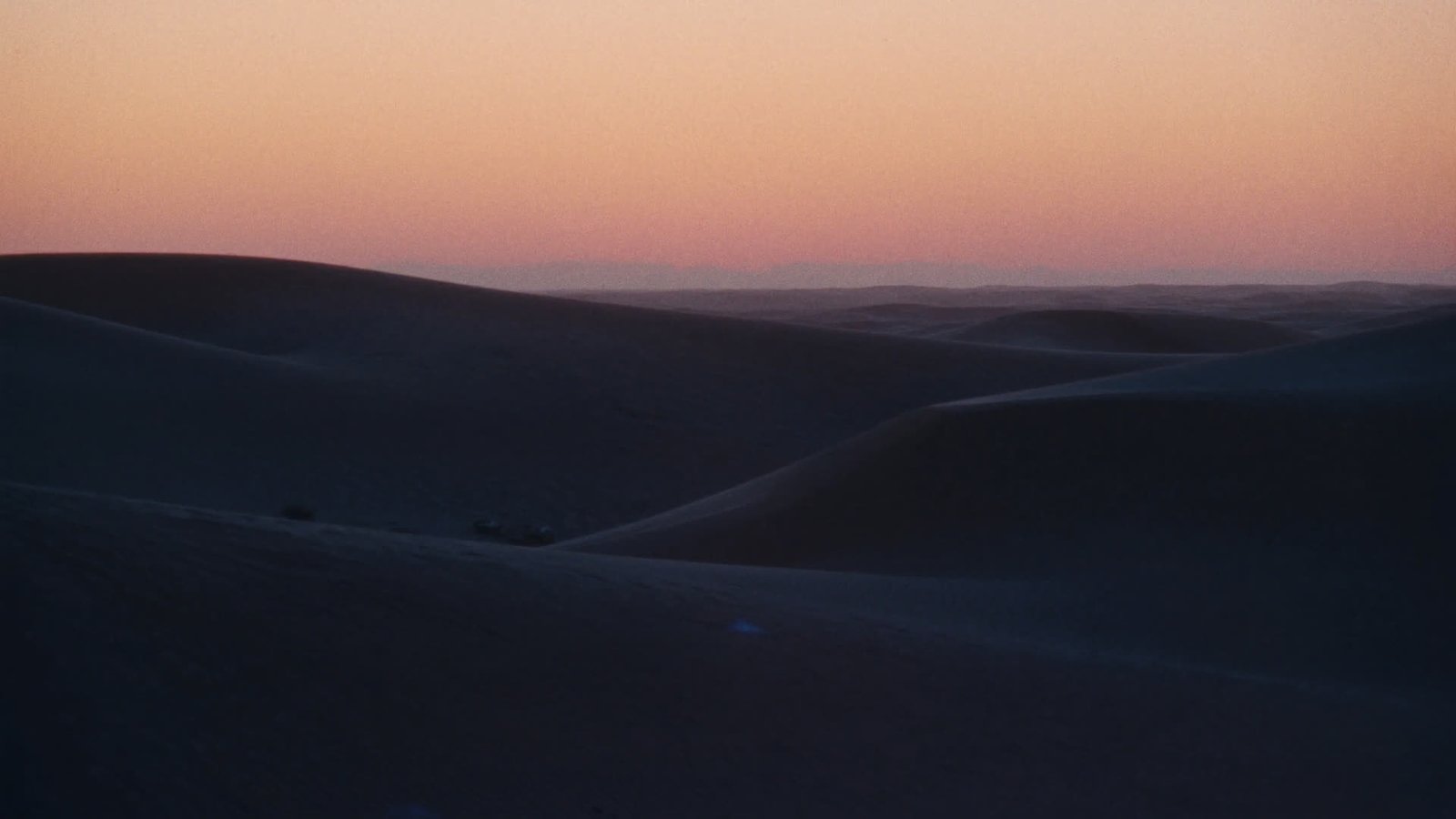 Erg Chegaga dunes at first light under a soft pink and gold gradient sky