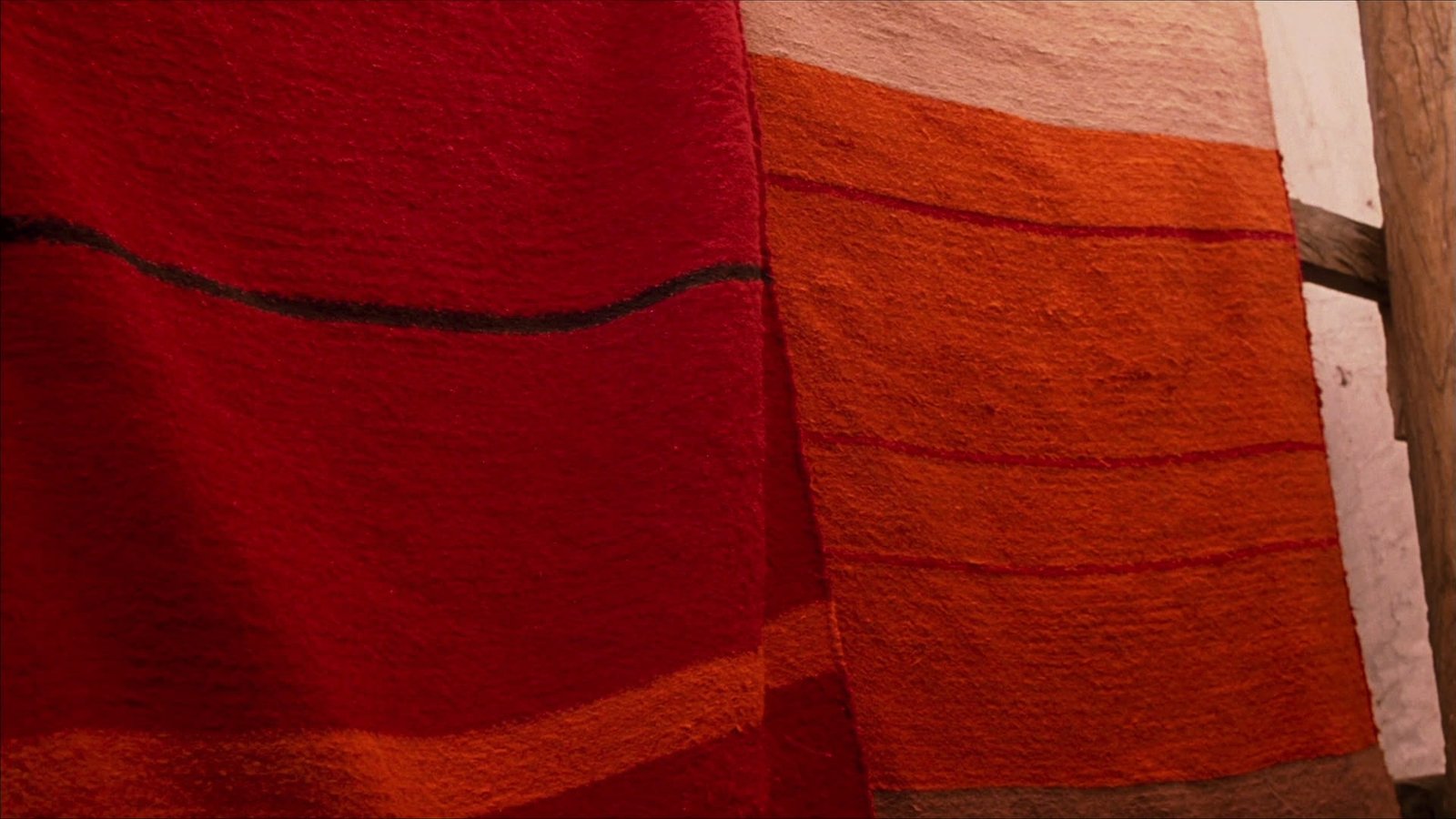 Hand-woven Berber carpets in reds and oranges hanging in a Tazenakht workshop
